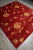 The rug seen from one corner, pile catching light so blossoms read pale gold