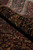 Rug rolled along the dark border, pile depth and gold floral drawing clearly visible