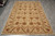 Rug laid flat on grey tile, seen lengthwise, showing staggered rows of floral palmettes