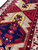 Angled close-up of two medallions, navy centre with red hooked motifs and sawtooth edging