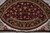 Angled view of the rug's near half showing black palmette border and knotted ivory fringe