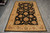 Rug laid flat on grey tile floor, full length shown with ivory fringe at the near end