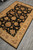 Diagonal view down the rug's length, black field and ivory border meeting the grey tiled floor
