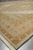 Side view of one end showing the banded borders and cream fringe against grey floor