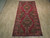Rug lying flat on a pale wood floor, white fringes at both ends, full length shown