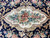Detail of the ivory centre cartouche filled with roses, blue blossoms and green leaves