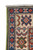 Corner detail showing ivory border rosettes, indigo guard band with red crosses, and white fringe