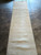 Runner photographed lengthwise in sunlight, the wool reading warm wheat where light crosses the pile