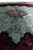 Low angle across the pile, medallion points meeting the black and burgundy field with silk sheen