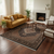 Rug staged in a living room with mustard sofa, round wood table and white fireplace