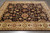 Rug photographed at an angle on grey stone, wide border filling the lower half of the frame