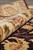 Rug rolled to display the border pile in section above the dark brown field