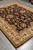 Full rug angled on grey tile, other rolled rugs visible in the corner behind