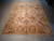 Whole rug laid on a concrete floor, inventory tags at the far corners, fringe nearest camera