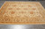 Rug laid on grey tile floor, viewed down its length with the gold border nearest