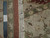 Back of the rug beside a ruler, showing knot density, woven border and white fringe