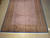 Rug photographed at an angle on concrete floor, ivory fringe and dealer tag at the near end