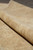 Rug rolled over itself, showing pile depth and the flat ivory ground of the border