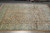 Rug laid on grey tile floor at an angle, rolled rugs stacked against the wall behind