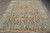 Full rug seen lengthwise from the fringed end, green border framing the sand coloured field