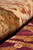 Rolled edge in low light showing pile depth across ivory border and burgundy field