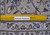 Ruler laid across the low pile beside an Authentic Handmade label, showing border knotting in detail