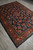 Diagonal full-length view of the rug on grey tile with fringe visible at the far corner