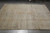 Angled full view of the hand-knotted wool rug with rolled inventory stacked behind it
