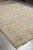 Room size 9x12 wool rug shown at an angle with corner fringe on gray flooring