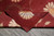 Folded corner exposing the finely woven back, selvage finish and burgundy underside of this handmade rug