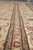 Narrow guard stripes with navy outlines and vine scroll along the border of this handmade rug