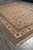 Full view of 8'6" x 11'6" khaki floral rug angled with ivory fringe in foreground