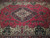 Close-up of navy medallion and floral vinework across the raspberry red field of this rug