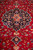 Angled view of the medallion and pendant with dense floral vines across the crimson field