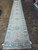 Extra long 3x20 hand-knotted wool runner laid out across tile floor in the Freeport showroom