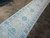 Angled view showing blue vase and pomegranate border framing the ivory field of this Khotan runner