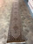 Hand-knotted Mahi fish pattern runner shown lengthwise in showroom with rust and camel tones