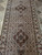 Angled view down the runner showing paired medallions, ivory guard stripes and brown borders