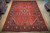 9'9" x 13'3" Sarouk rug photographed flat on warehouse floor showing rust field and navy border