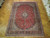 9'8" x 13' Kashan Persian rug laid flat on parquet floor showing red field and teal guard borders