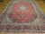 Angled view of the 10x13 hand-knotted wool Kashan showing navy spandrels and layered floral border stripes