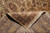 Folded corner reveals dense hand-knotted wool back beside gold border and ivory cotton fringe