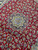 Close-up of the all-over floral field surrounding the star medallion on tomato red wool