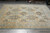 Hand-knotted Pakistani wool rug photographed in the showroom with stacked and rolled rugs behind it