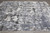 Modern wool and silk rug photographed on gray tile floor showing organic charcoal and ivory pattern