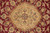 Close-up of the gold oval medallion with green, coral and black floral tracery on red