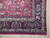Corner detail of navy boteh paisley border framing the raspberry red floral field and fringe