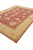 Living room size wool rug tilted to show thick pile, ivory border and red outer edge