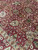 Olive green and ivory blossoms scattered over the rust red field of this Indian rug