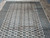 Large neutral beige area rug photographed overhead, soft storage fold shadows across the wool pile